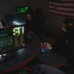 A man and woman working on computers with data on the screen