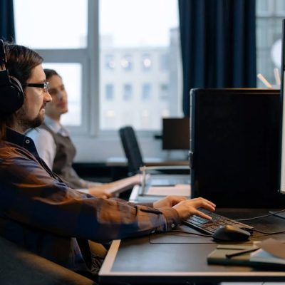 Man sitting at desk working on computer with headphones on.